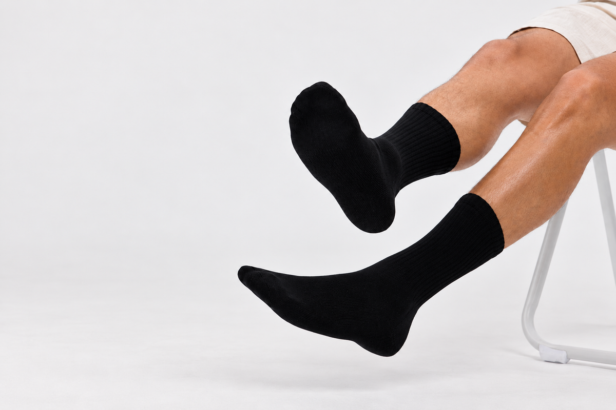 Black Base Supply ribbed crew socks worn by a seated model against a light studio background