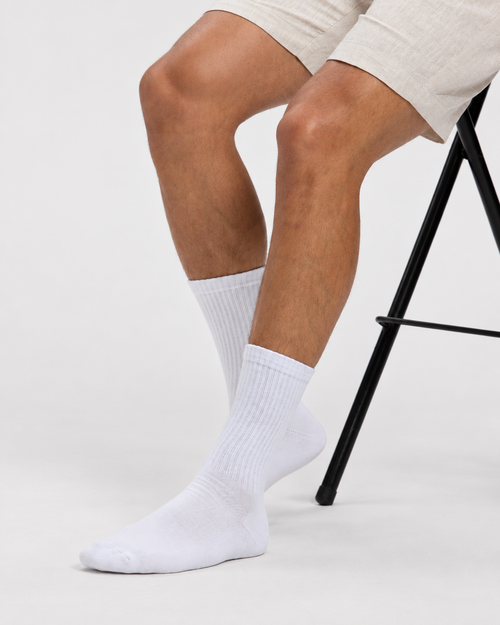 Base Supply white ribbed crew socks worn by a seated model