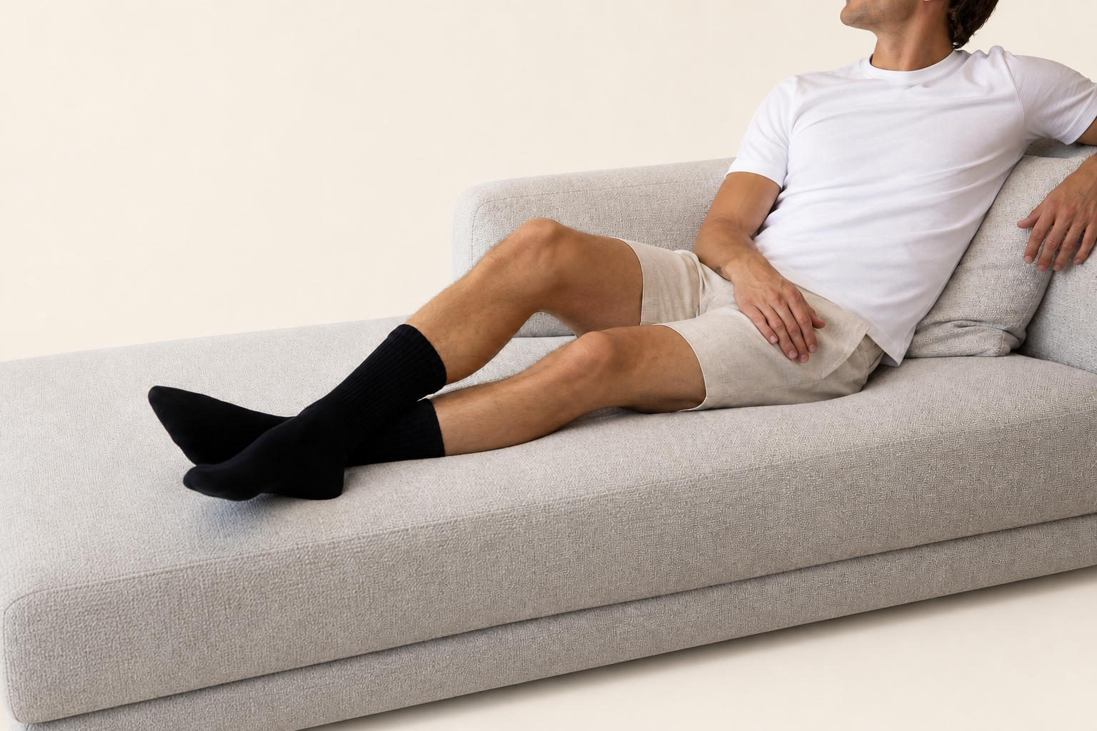 Model resting on a couch wearing black Base Supply crew socks, photographed without a direct face view